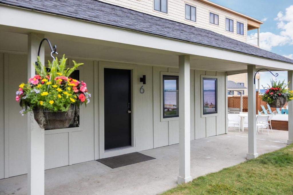 a white house with a porch with flowers on it at Newly Remodeled Bayview Cabin 6! in Traverse City
