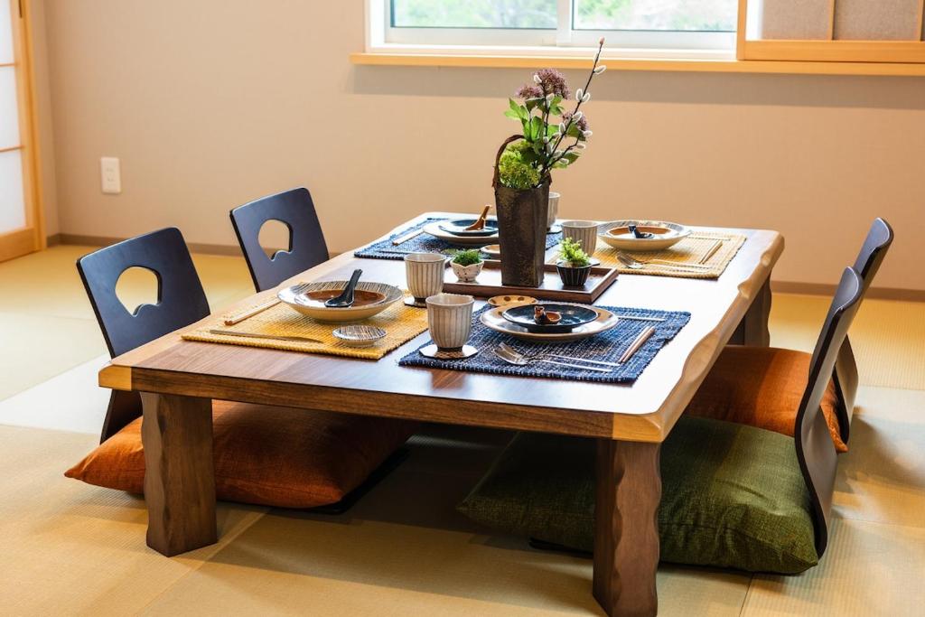 a wooden table with dishes and flowers on it at MEIBI Hakone Yumoto in Hakone