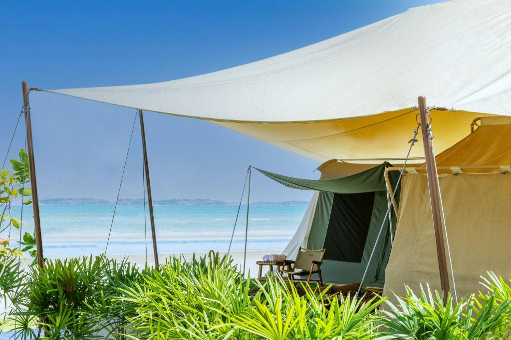 a tent on the beach with the ocean in the background at Camp Cayla - COASTA in Ban Ao Makham Pom