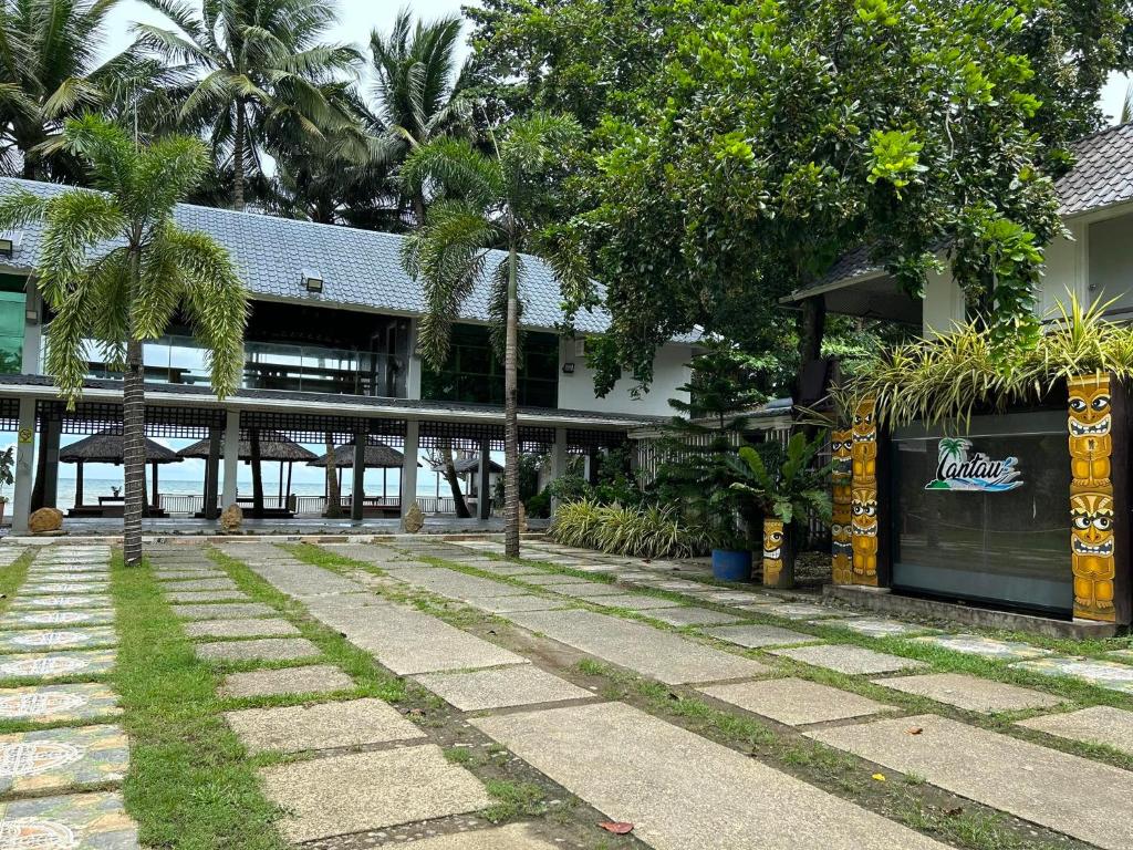 a building with a walkway and palm trees in front of it at Lantau Beach Resort in Tukuran