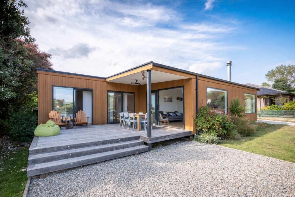 a small house with a wooden deck and glass doors at Pohara's Beach Escape in Pohara