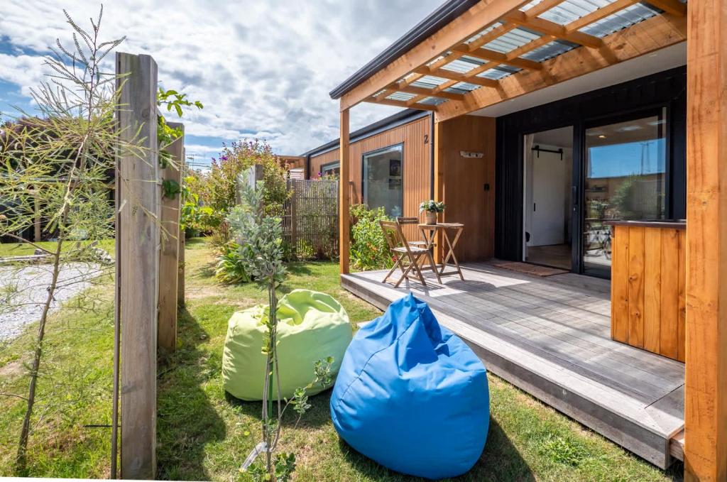 a house with a garden and a wooden deck at Pohara Beach Pukeko Studio in Pohara