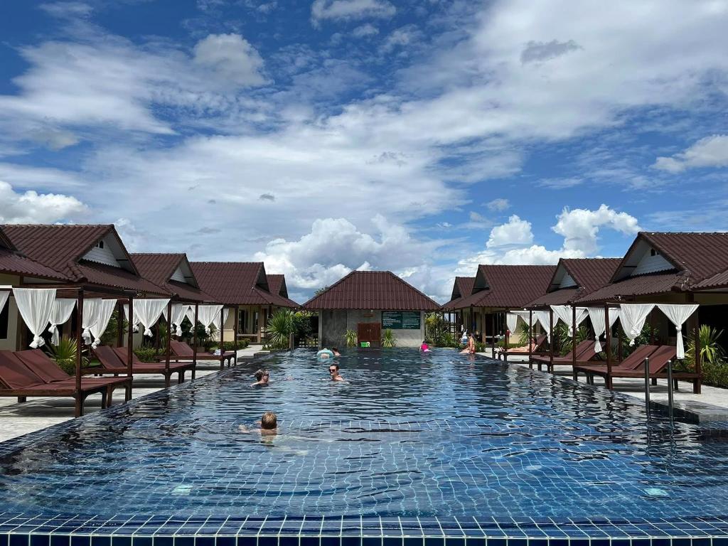 a swimming pool with chairs and people in the water at Bu-Gaan Sukhothai Village in Sukhothai
