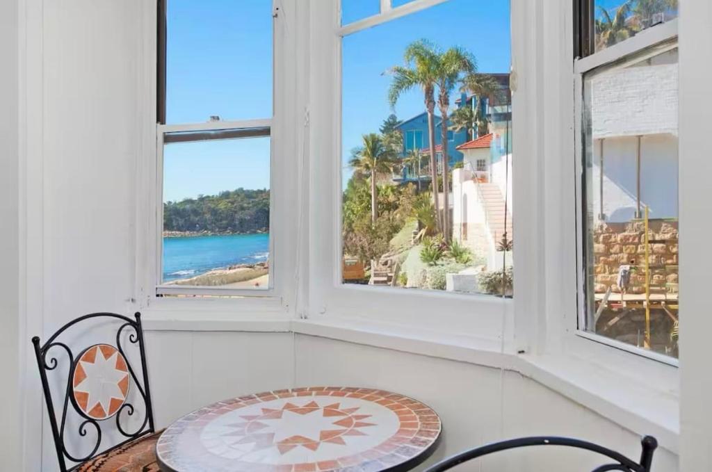 a room with two windows and a table and chairs at Ocean Studio along Shelly Beach in Sydney