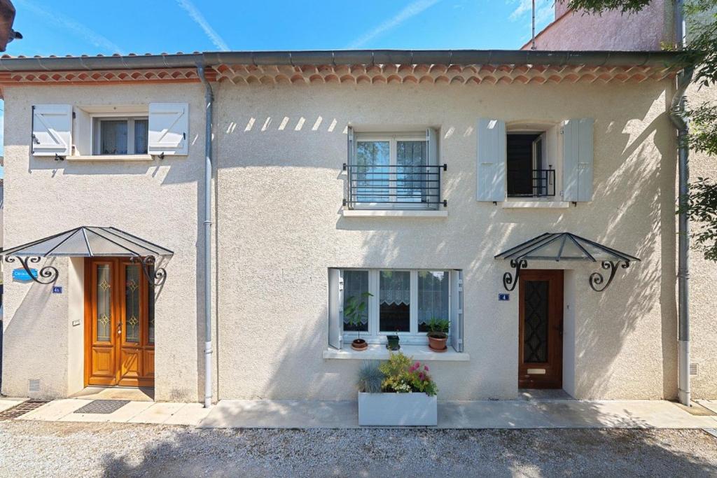 a white house with two doors and two windows at Gîte les mésanges in Castres