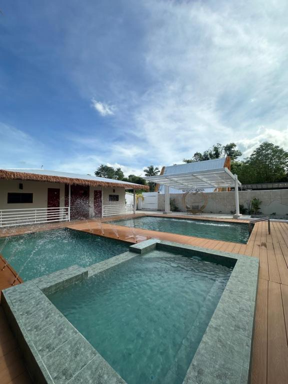 a swimming pool with a wooden deck and a house at SeventhHeaven Nasugbu in Reparo