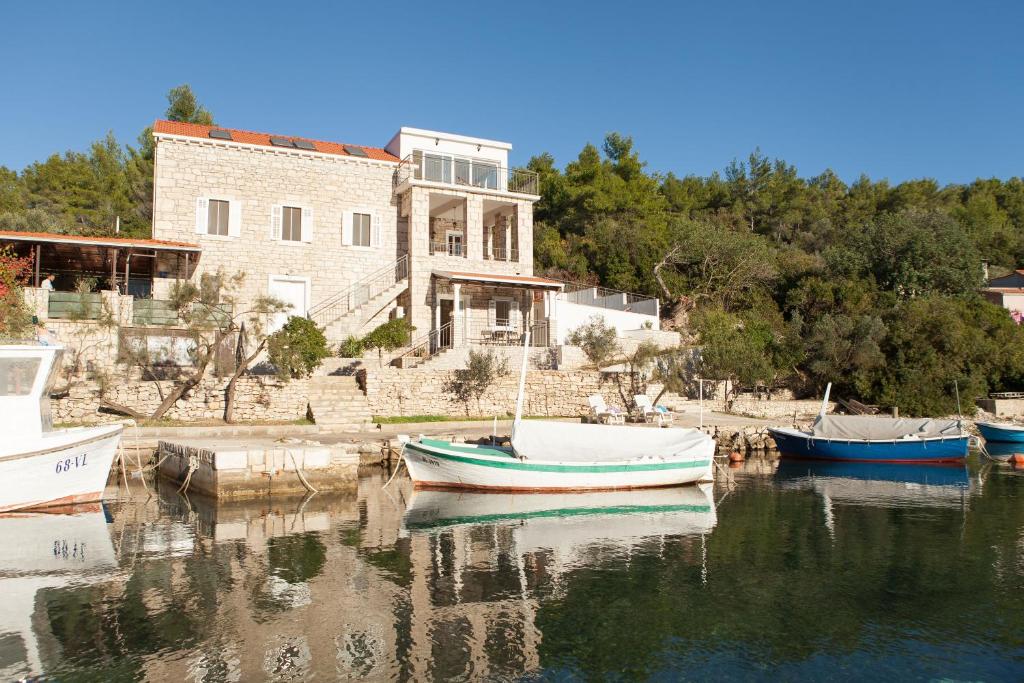 a group of boats in the water in front of a building at Stone House Villa Darinka in Vela Luka