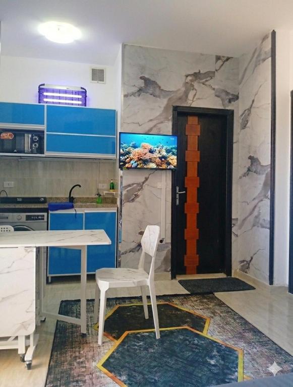 a kitchen with a table and a chair and a door at Wavesong Whispers flat where you can enjoy seaview with the best price and enjoy speedy wifi for forigners only ممنوع المصريين in Hurghada