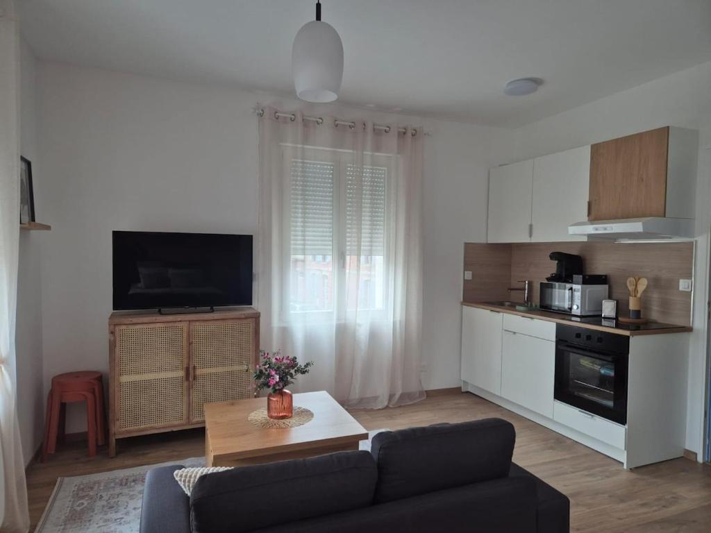 a living room with a couch and a kitchen at le st fursy 1 in Péronne