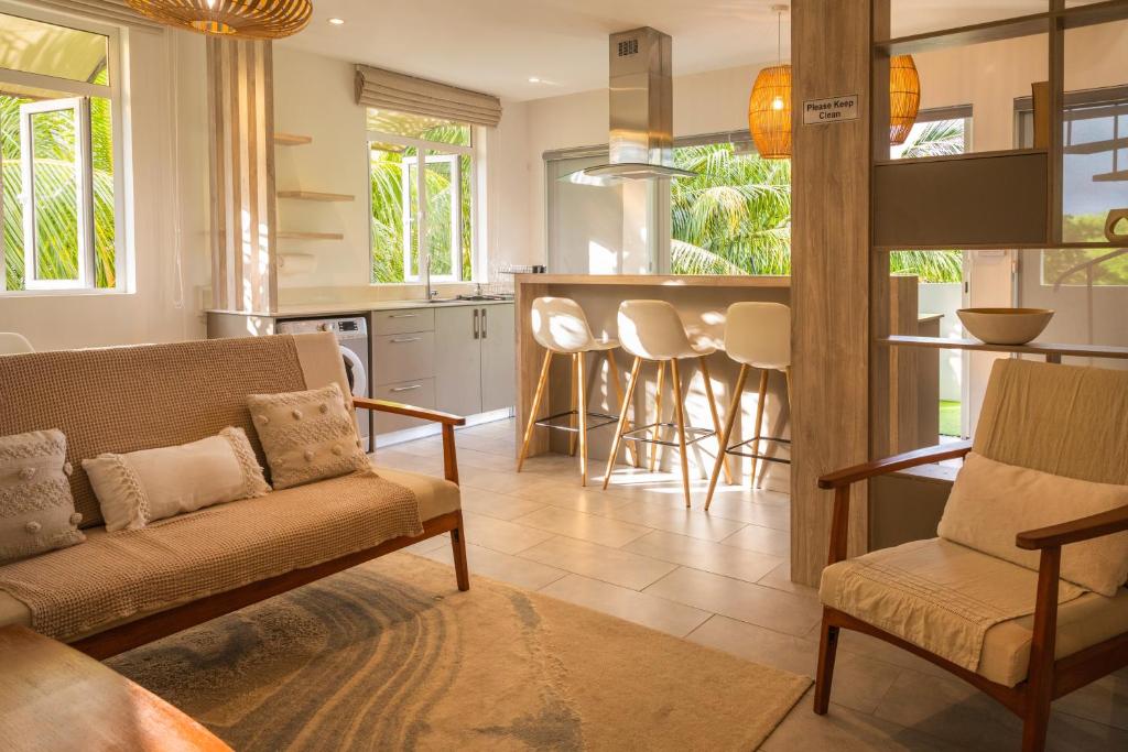 a living room with a couch and a kitchen at ELYMUS - Spacious 3-Bedroom Apartment With Private Rooftop and Balcony - Near Le Morne And Lagoon in La Gaulette