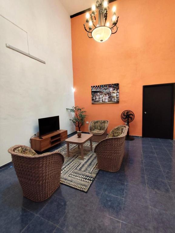 a living room with chairs and a table and a tv at Casa colonial tranquila cerca del centro, Casa Solecito in Valladolid
