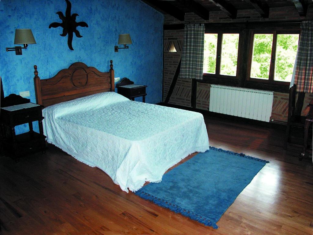 ein Schlafzimmer mit einem Bett und einer blauen Wand in der Unterkunft Aristieta in Ajangiz