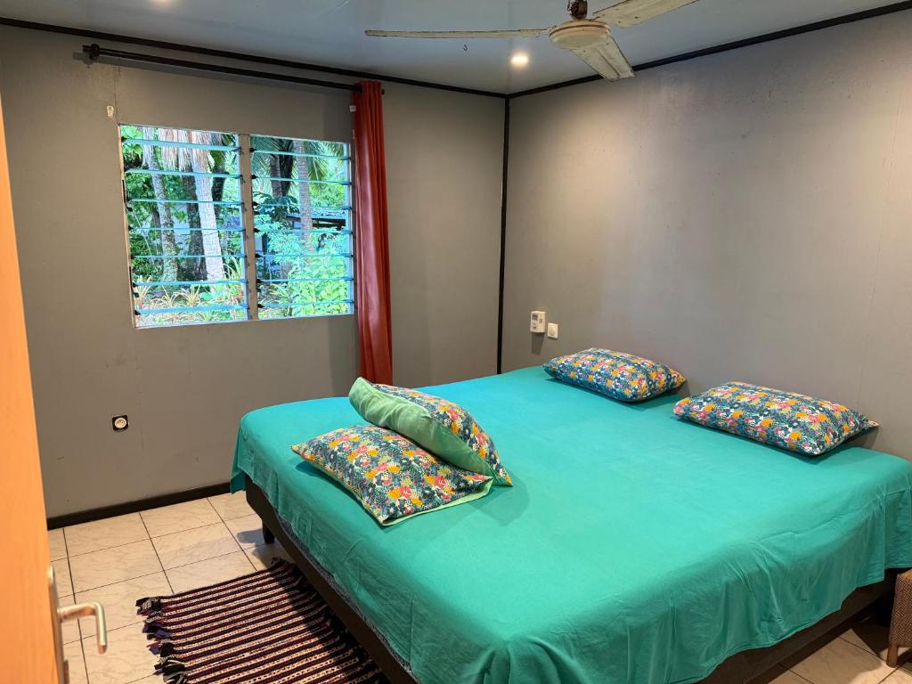 a bedroom with a green bed with pillows and a window at Le Petit Coin de EDEN in Parea
