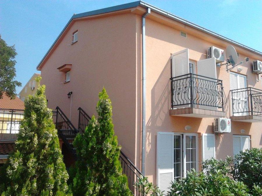a large pink building with balconies and trees at Apartments Eden in Jadranovo
