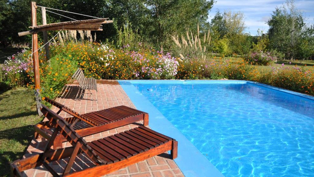 una piscina con 2 tumbonas y una piscina en El Caserio Casas de Campo en Villa Cura Brochero