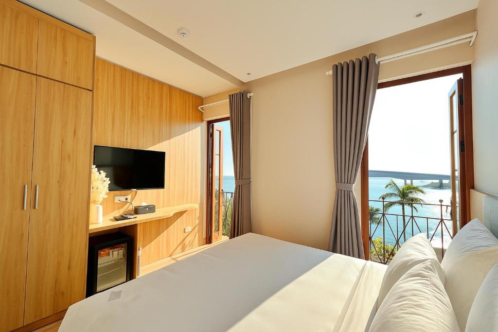 a bedroom with a bed and a tv and a window at HANZ Lagoon Sunset Hotel in Phú Quốc