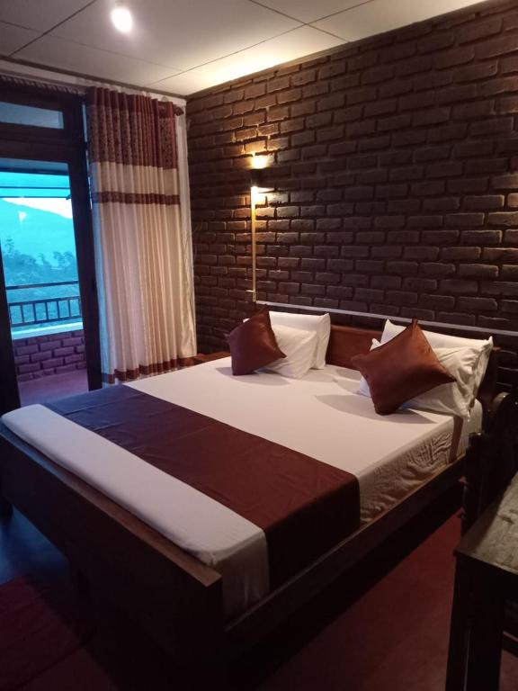 a bedroom with a large bed with a brick wall at Diduli Hotel in Ella