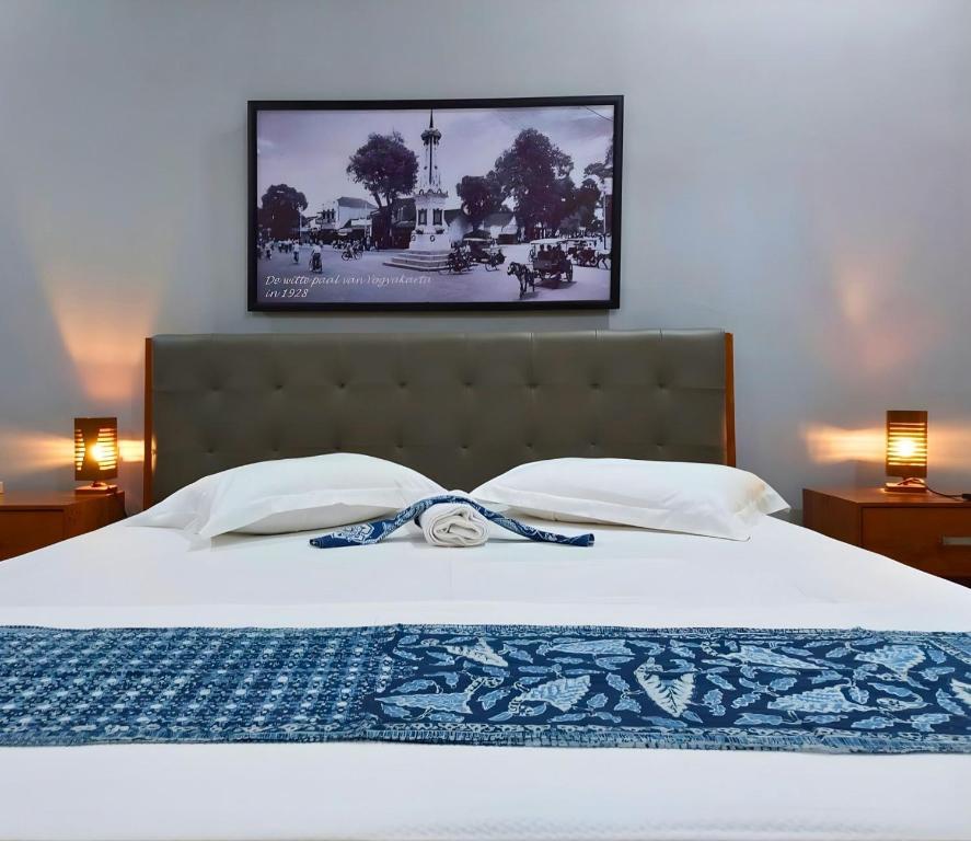 a bedroom with a white bed with a picture on the wall at Hamemayu Homestay in Jejeran