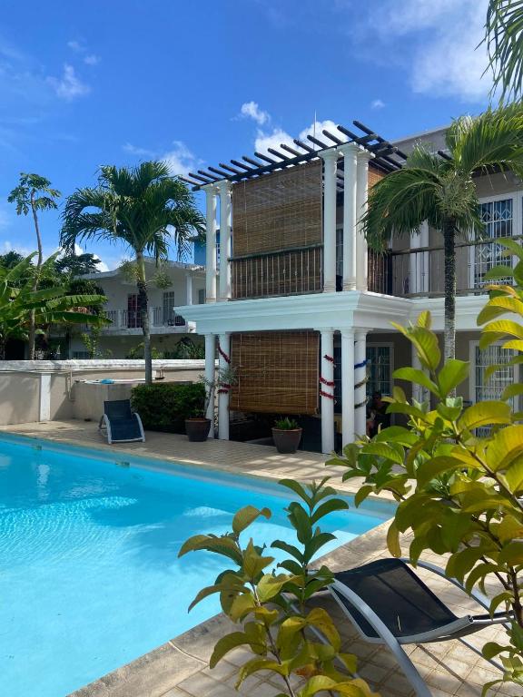 a villa with a swimming pool in front of a house at Solmera Villa in Grand-Baie