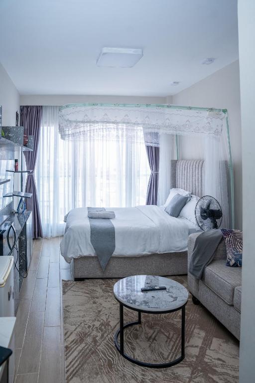 a bedroom with a bed and a couch and a table at Taurus B8-6 in Nairobi