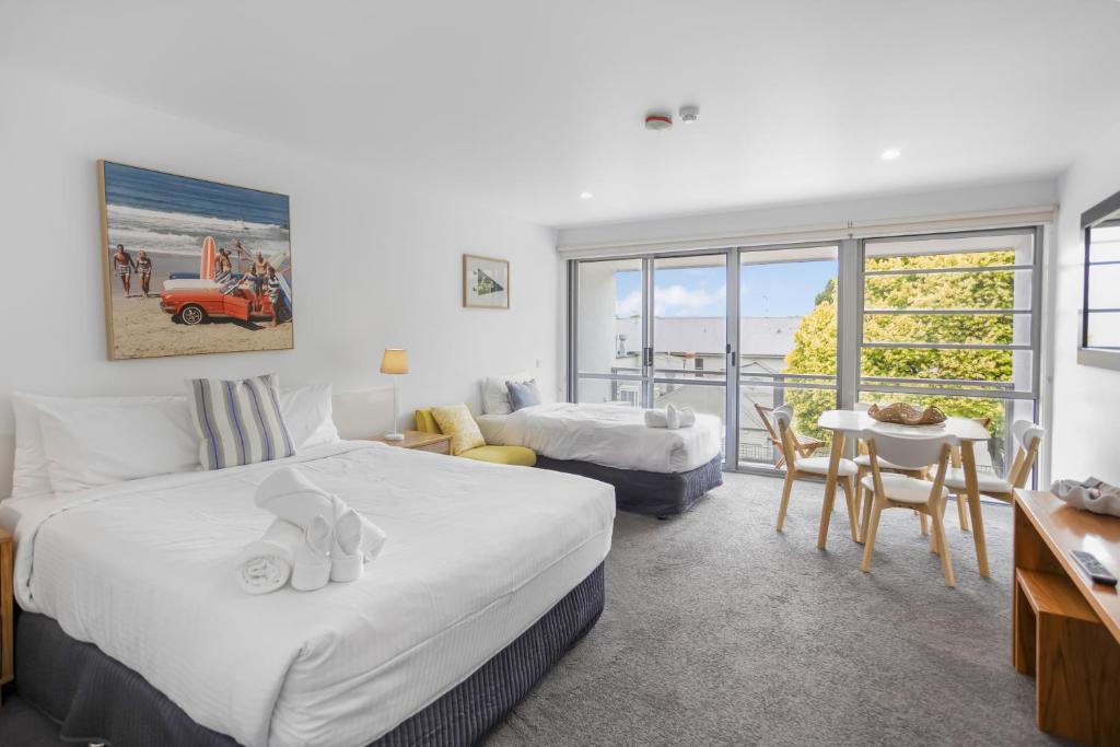 a hotel room with two beds and a table and chairs at Bay View - The Trio in Lorne