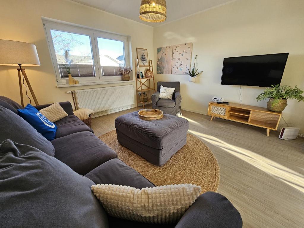 a living room with a couch and a flat screen tv at Küstenglück 2 Stylisches Apartment mit Meerblick - 200m zum Strand & Bäcker in Dahme