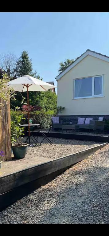 a table with an umbrella in front of a house at Rosehill annexe in Knighton