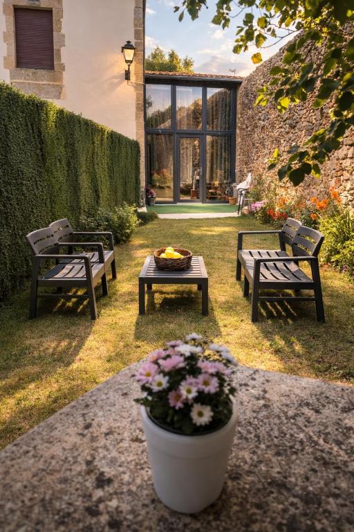 a patio with two benches and a table and flowers at O Cabanel in Fisterra