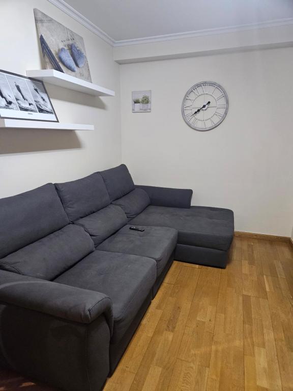 a living room with a couch and a clock on the wall at apartamento castelao in Cedeira