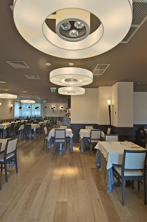a dining room with tables and chairs and a large ceiling at Zen Hotel Versilia in Marina di Pietrasanta
