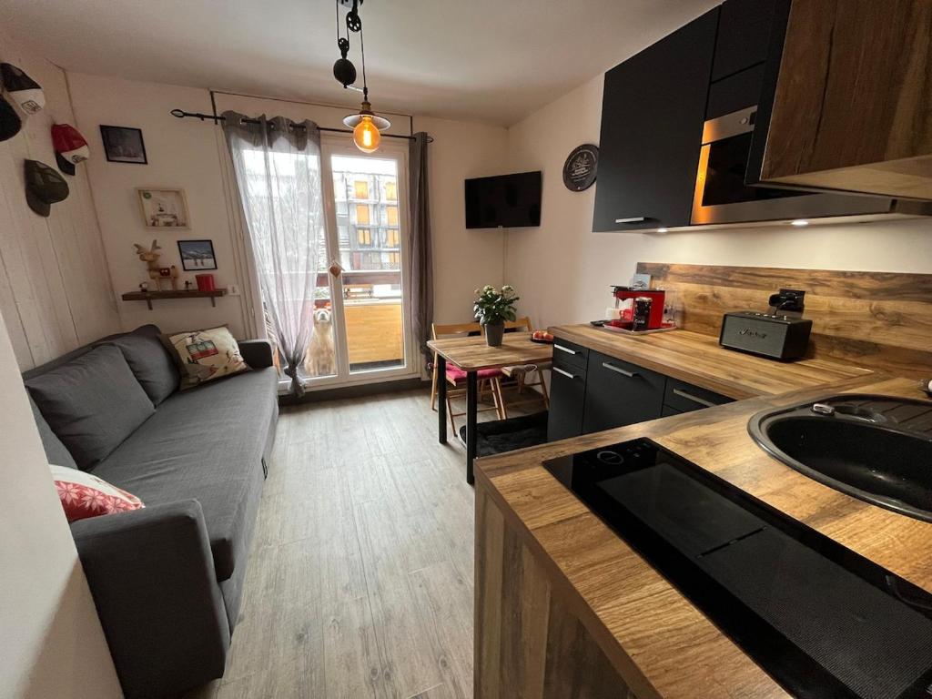 a living room with a couch and a kitchen at Ada & Cimes in Bourg-Saint-Maurice