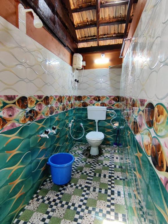 a bathroom with a toilet and a painting on the wall at patanga beach cottege in Gokarna