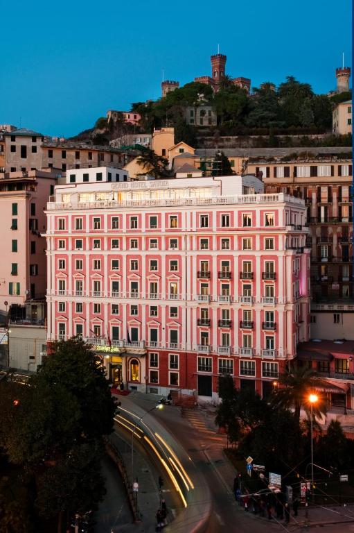 a large pink building on a city street at Grand Hotel Savoia in Genoa