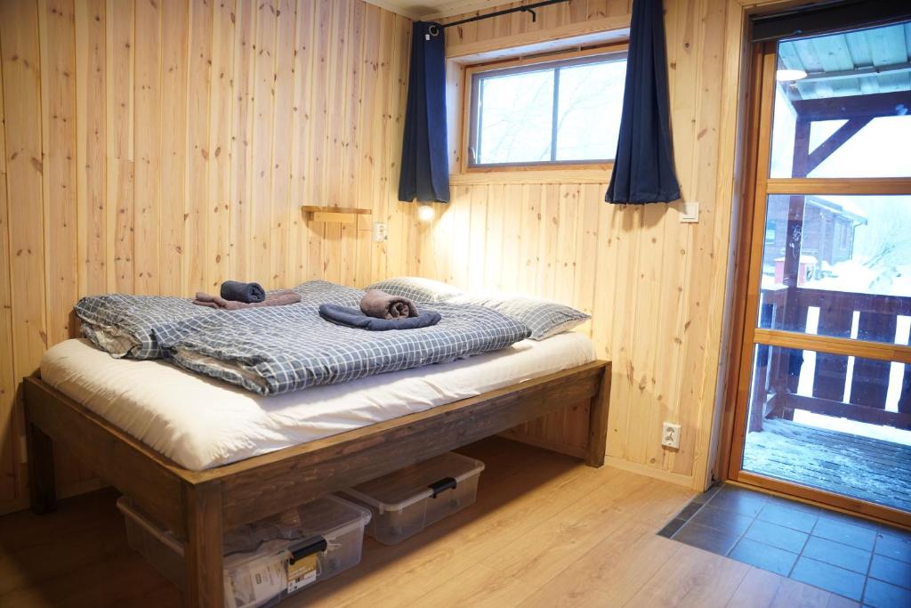 a bed in a wooden room with two people on it at Ingridstua Huskyfarm Innset in Bardu
