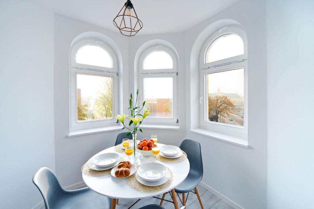 a white dining room with a white table and chairs at Apartamenty River View od WroclawApartament-pl in Wrocław