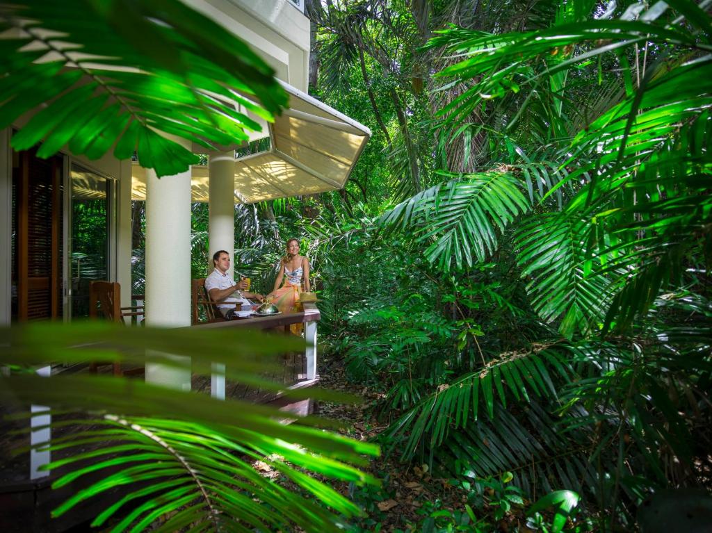 due persone sedute su un portico di una casa con alberi di Green Island Resort a Green Island