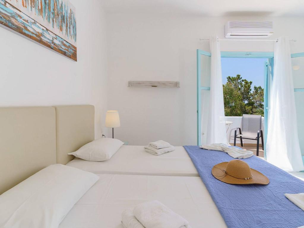 a white room with two beds with a hat on it at Makrigialos Apartments und Studios in Makry Gialos