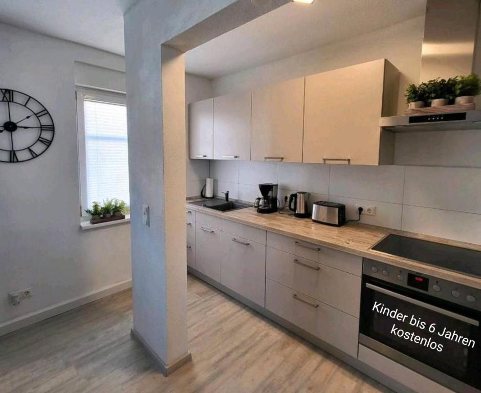a kitchen with white cabinets and a clock on the wall at Ferienwohnung NR1 in Großräschen
