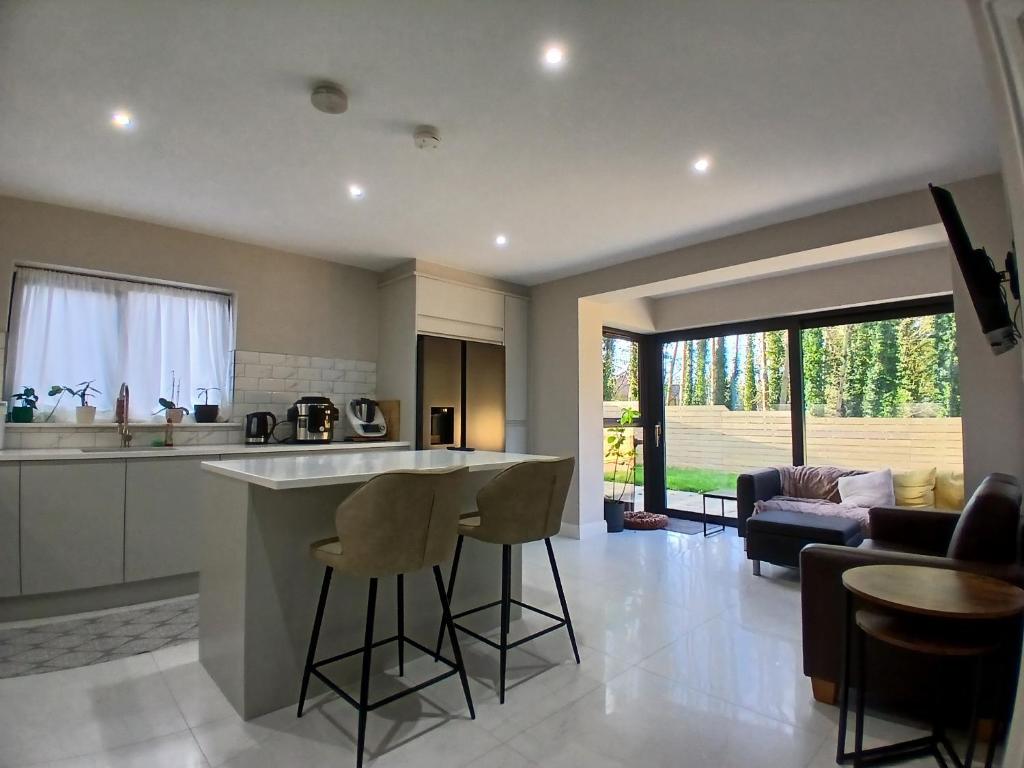 a kitchen and living room with a counter and stools at Private room in shared house at Casa de Charlie in Lambeg