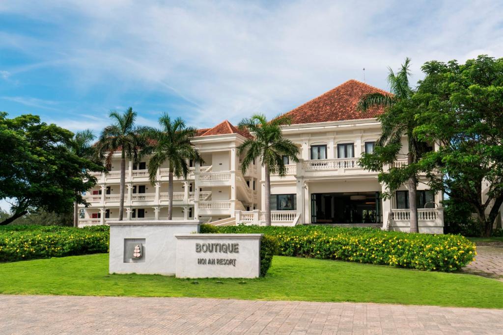 een groot wit gebouw met een bord ervoor bij Boutique Hoi An Resort in Hội An