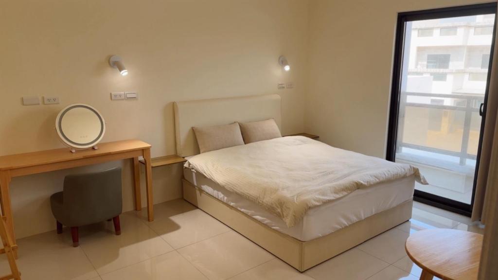 a bedroom with a bed and a desk and a mirror at Grass in the Wind B&B in Magong