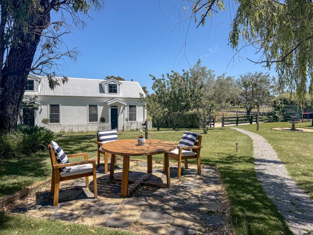 a wooden table with four chairs in a yard at Clonmara Country House and Cottages in Port Fairy