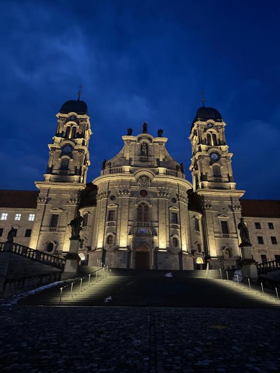 a large building with two towers at night at Klostergarten in Einsiedeln