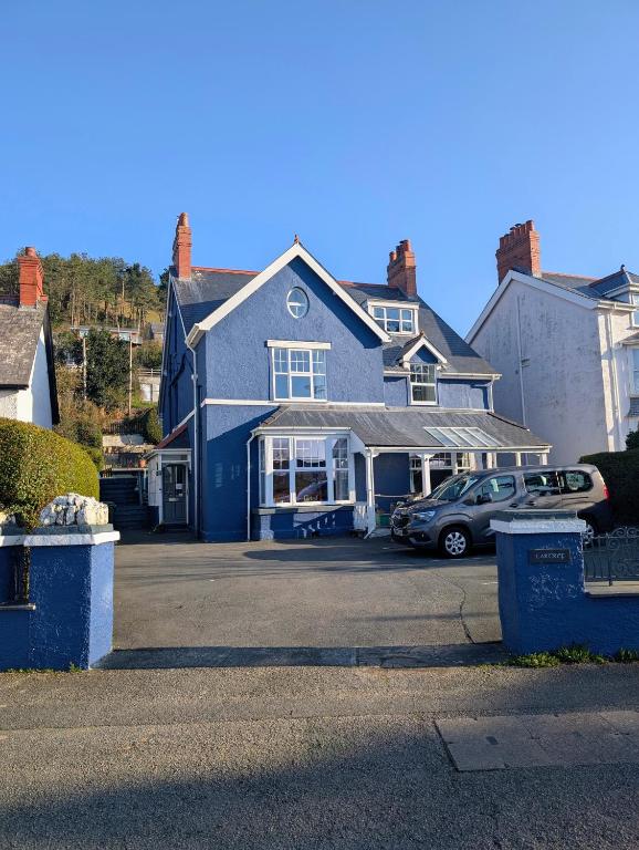 a blue house with a car parked in a parking lot at Cartref Guesthouse - Room 2 Ensuite in Aberdyfi