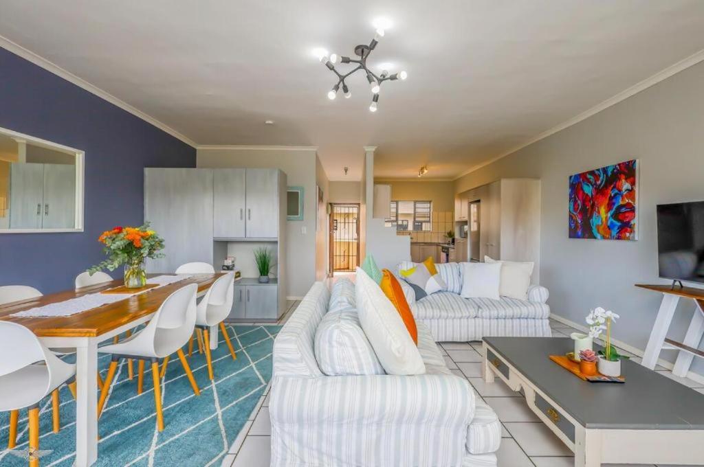 a living room with white furniture and a dining room at Flip-Flop Flat in Langebaan