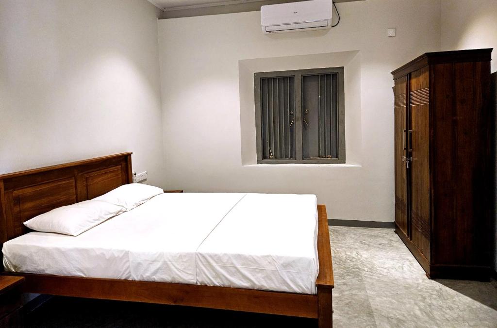 a bedroom with a white bed and a window at Gate House Mirissa in Mirissa