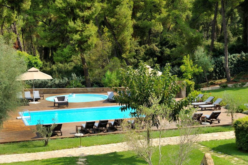 a swimming pool in a garden with chairs around it at Sani Polyastron Hotel & Spa in Sani Beach