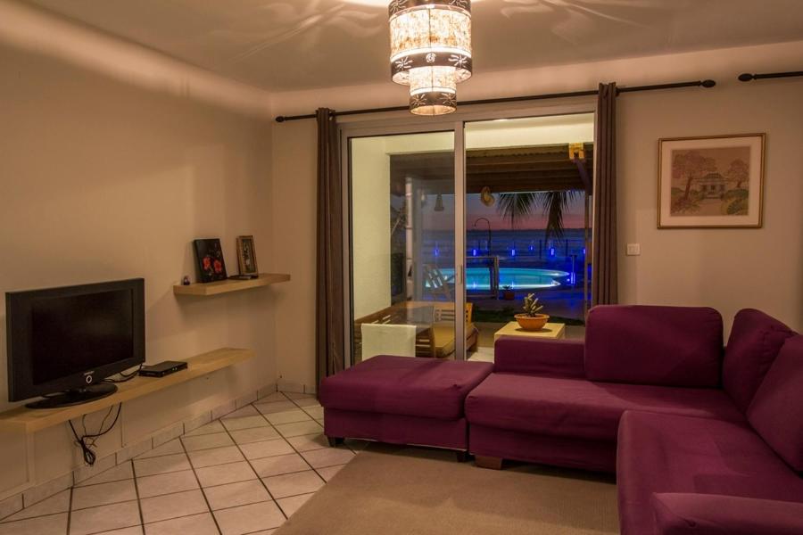 a living room with a purple couch and a tv at Leu Pied Dans L&#39;Eau in Saint-Leu