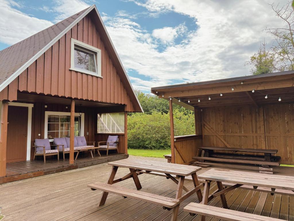 a wooden deck with picnic tables and a building at Diby Kämping saunamaja numbritoad in Diibi