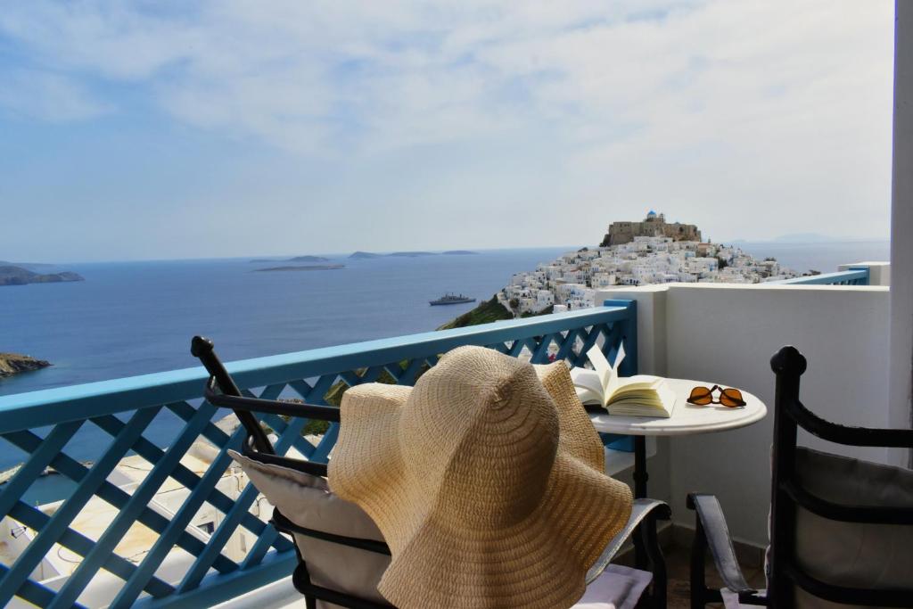 a hat sitting on a chair on a balcony overlooking the ocean at Catsalos Studios in Pera Gyalos